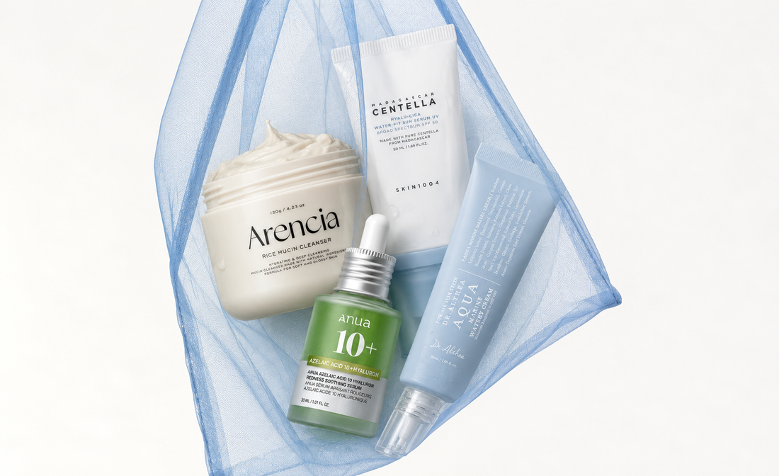 Arencia Rice Mucin Cleanser, Anua Azelaic Acid 10+ serum, SKIN1004 Centella sunscreen, and Dr. Althea blue cream naturally arranged in sheer light blue mesh on a white background.