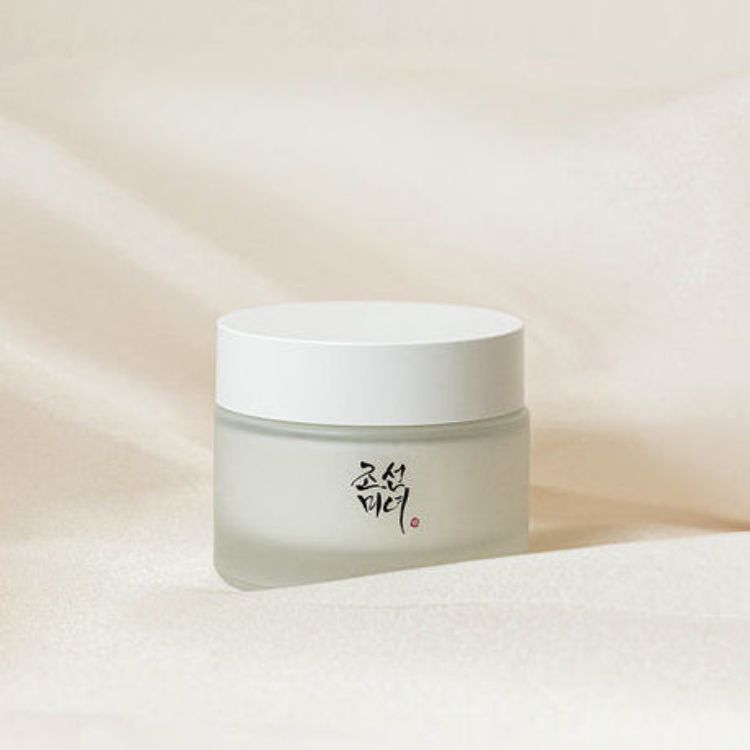 A Beauty Of Joseon Dynasty Cream with a white lid, featuring black Korean calligraphy on the front, set against a soft beige textured background.