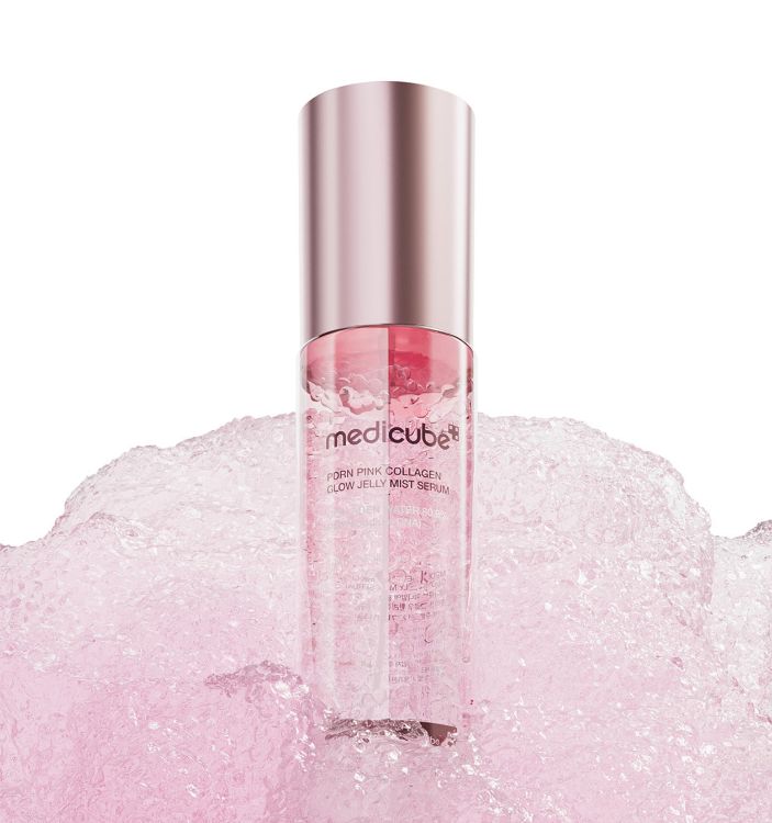 A clear cylindrical bottle of Medicube PDRN Pink Collagen Glow Jelly Mist Serum with a metallic rose gold cap, standing upright in a bed of pink gel against a white background.