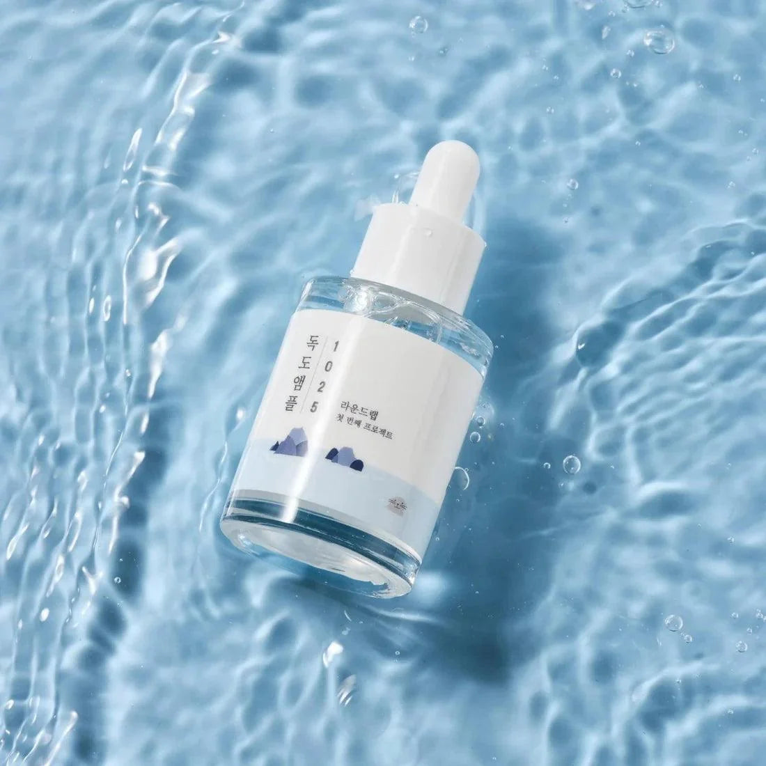Round Lab 1025 Dokdo Ampoule with blue liquid on water surface