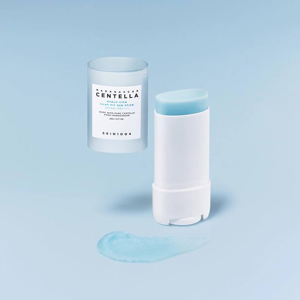 SKIN1004 Madagascar Centella Hyalu-Cica Silky-Fit Sun Stick shown with its cap off, floating above a smear of the light blue gel on a soft light blue background.