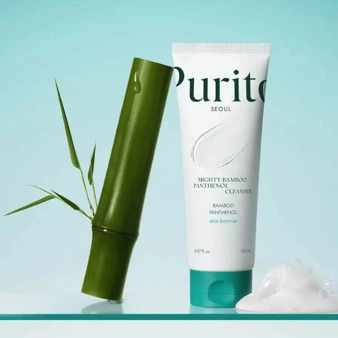 Purito Seoul Mighty Bamboo Panthenol Cleanser in a white squeeze tube with a teal cap, shown next to a green bamboo stick and a dollop of white cleanser on a light blue background.