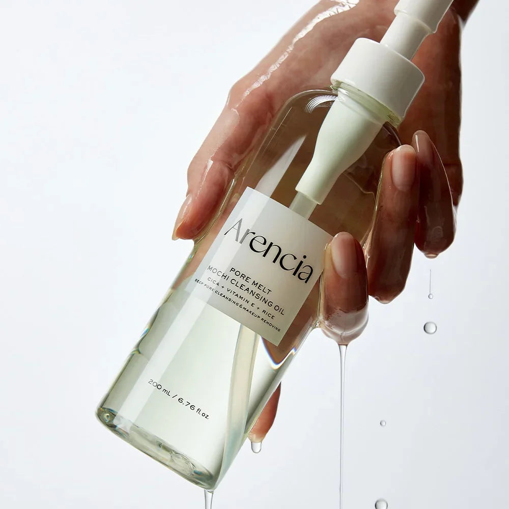 Hand holding a bottle of Arencia Pore Melt Mochi Cleansing Oil  with dropper on a light background