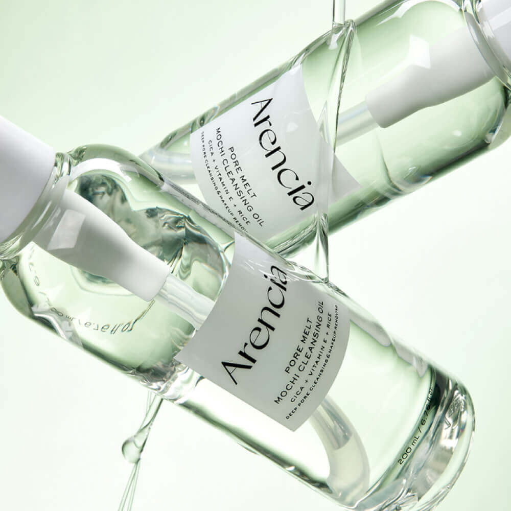 2 clear glass bottles of Arencia Pore Melt Mochi Cleansing Oil  arranged diagonally on a clean white background, with liquid dripping from the dropper tops.
