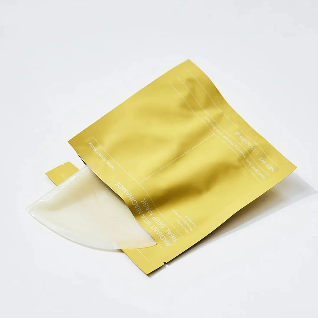 A single Biodance Radiant Vita Niacinamide Real Deep Mask in a translucent off-white color, partially tucked inside a metallic gold foil pouch with white text, set against a clean white background.