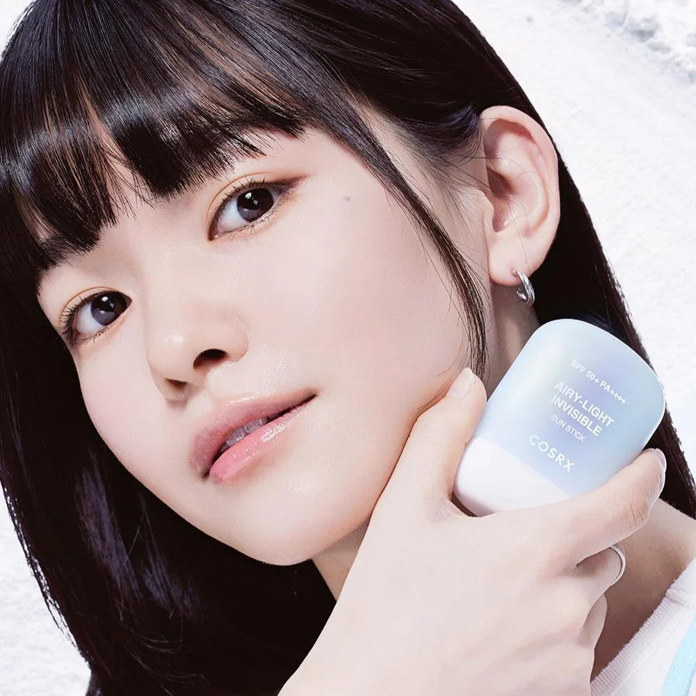 Woman holding a COSRX Airy-Light Invisible Sun Stick 19g  with a blurred background