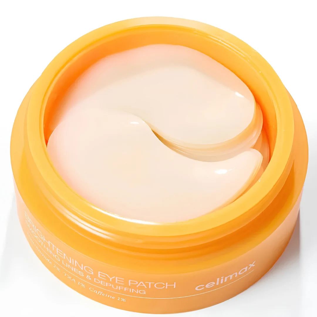 A round orange cosmetic jar containing pale peach eye patches, with Celimax TXA Brightening Eye Patch text visible on the front, set against a clean white background.