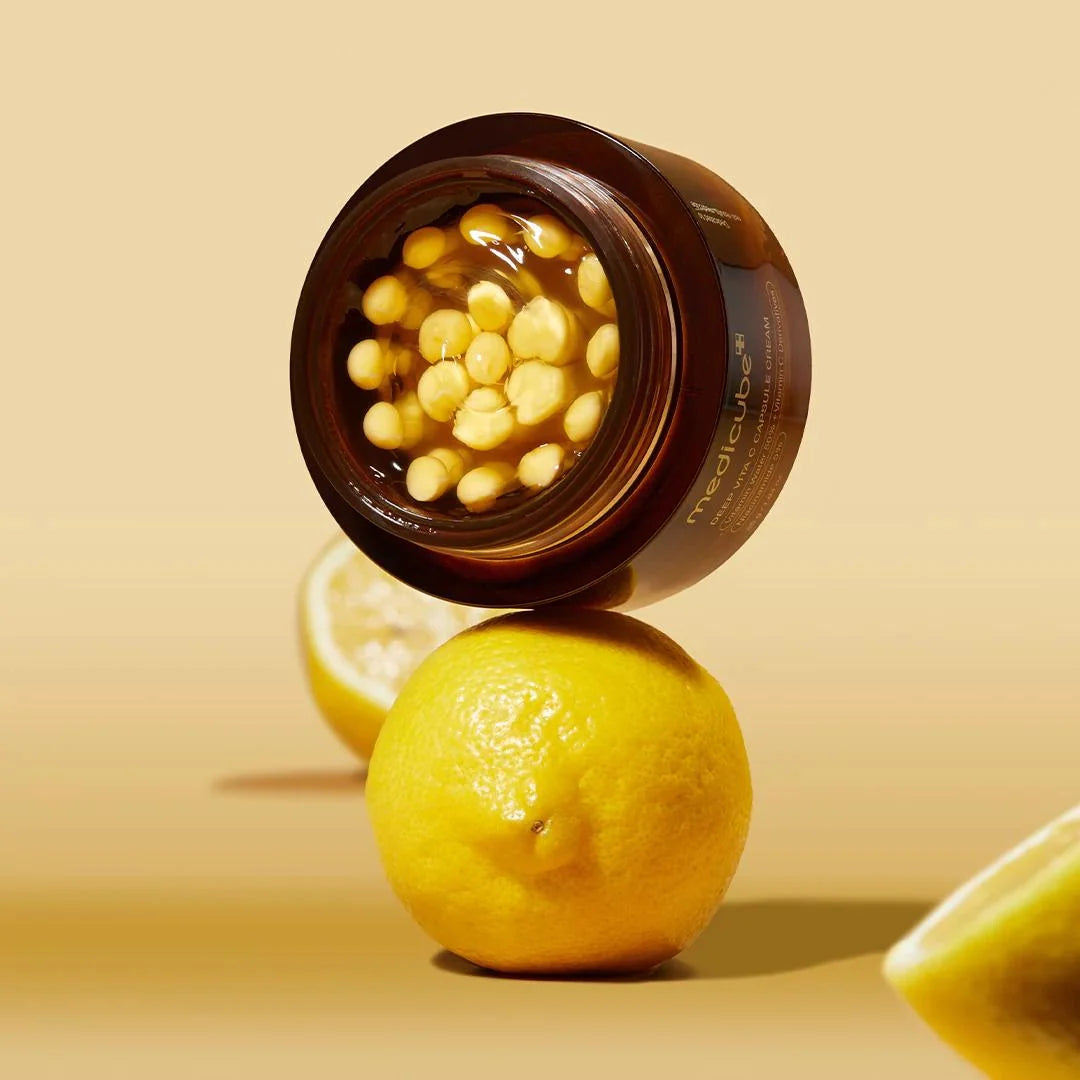 Medicube Deep Vita C Capsule Cream with lemons on a beige background