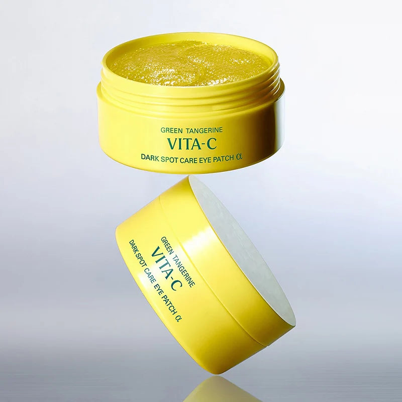 Yellow cosmetic jar of Goodal VITA-C Dark Spot Care Eye Patch with green tangerine gel, shown open with the lid floating below on a light gray gradient background.