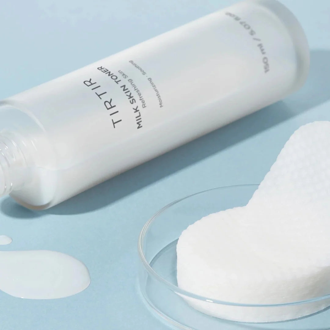 TIRTIR milk skin toner bottle with a white sponge on a light blue background