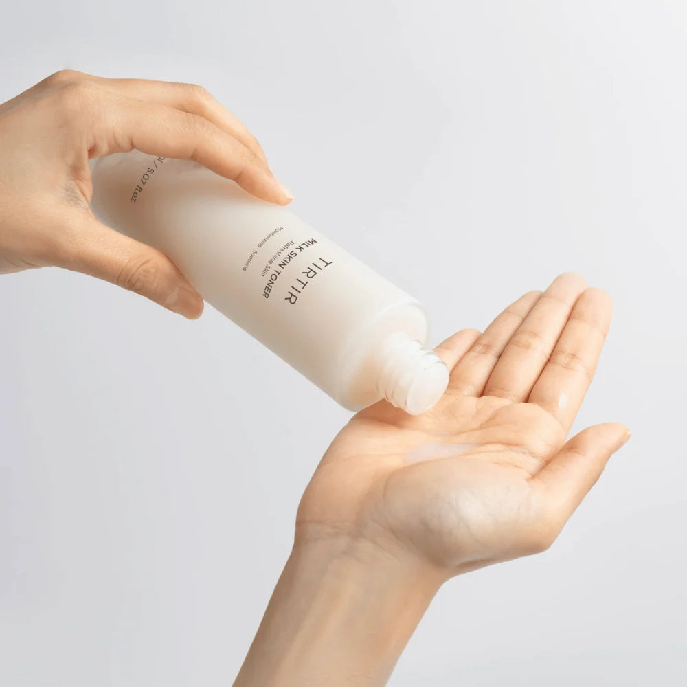 Hand applying TIRTIR Milk Skin Toner on a light background