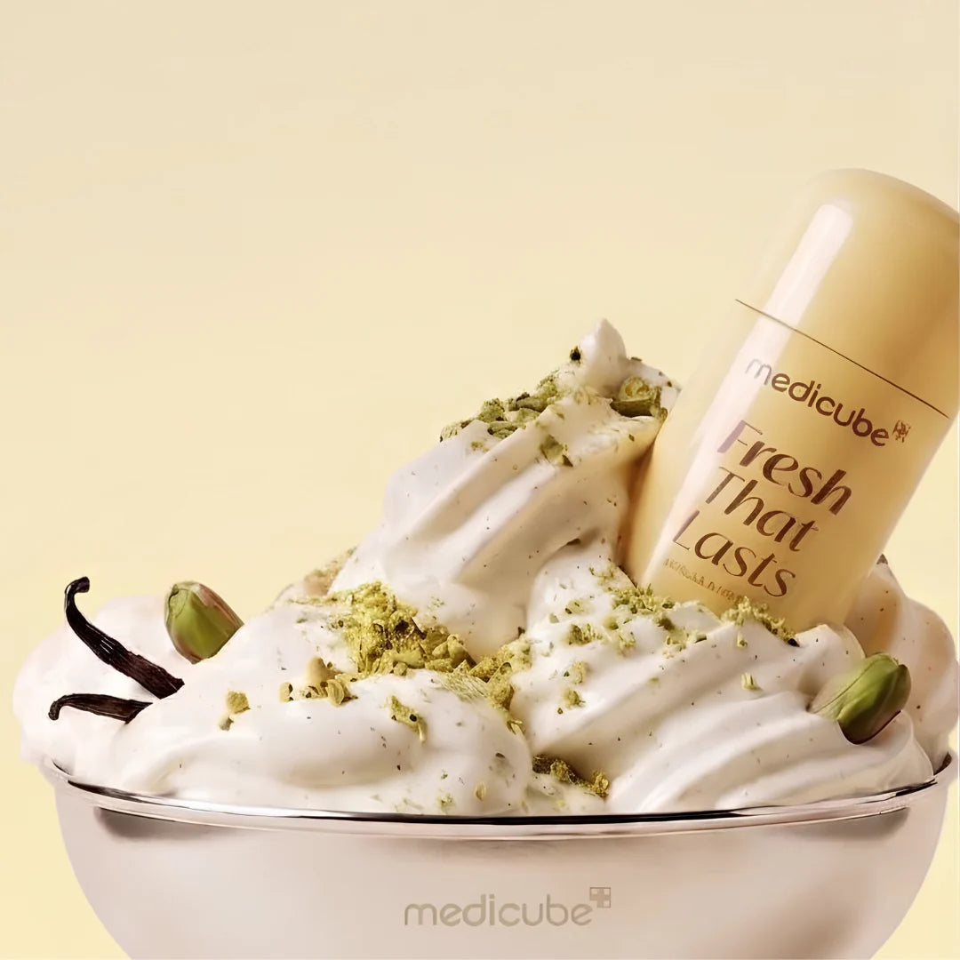 A medicube Fresh That Lasts deodorant stick displayed in a decorative bowl filled with whipped cream, green pistachio crumbs, vanilla beans, and green pistachio pods, set against a solid pale yellow background.