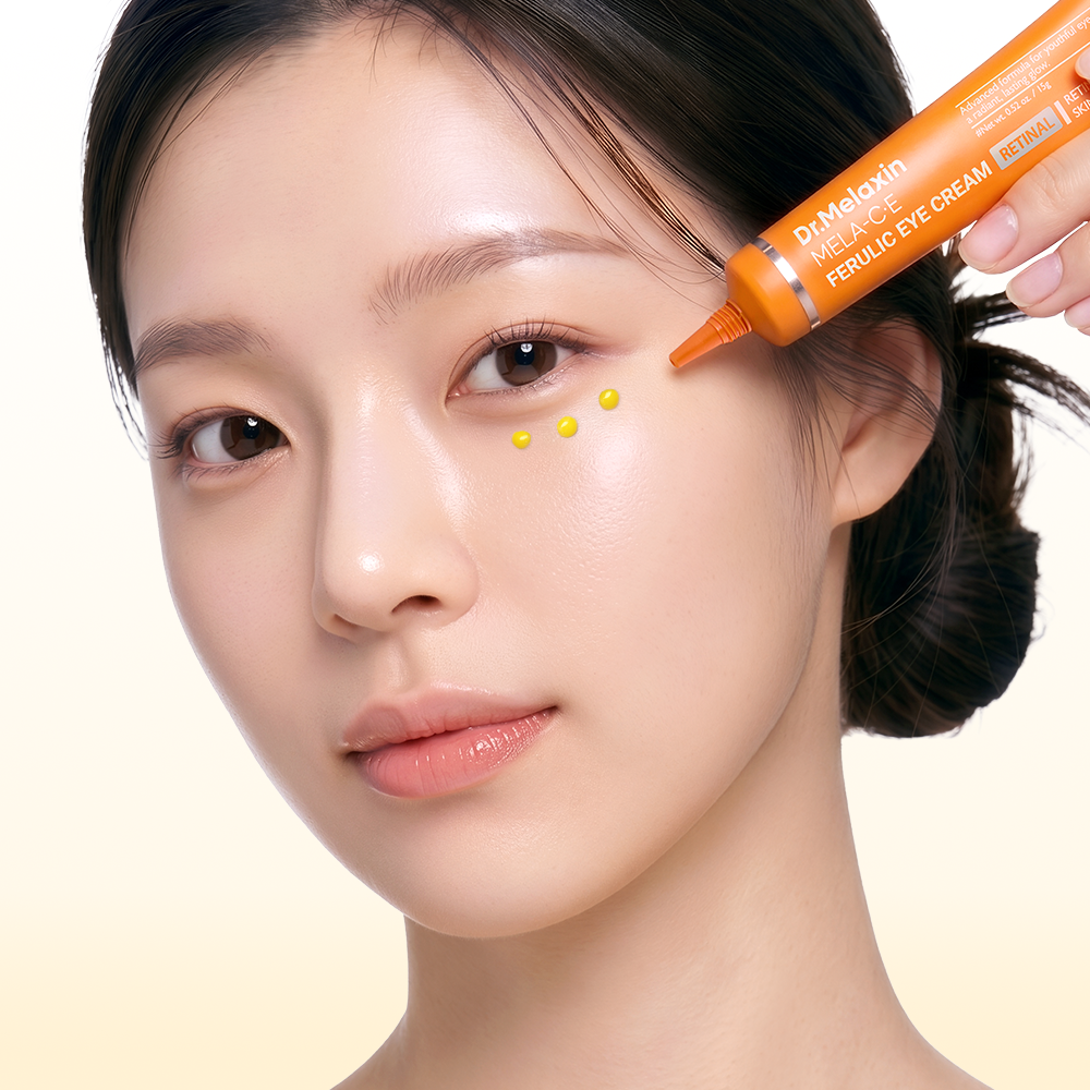 Close-up of a woman holding an Dr.Melaxin Mela-CE Ferulic Eye Cream, with yellow dots applied under her eyes.