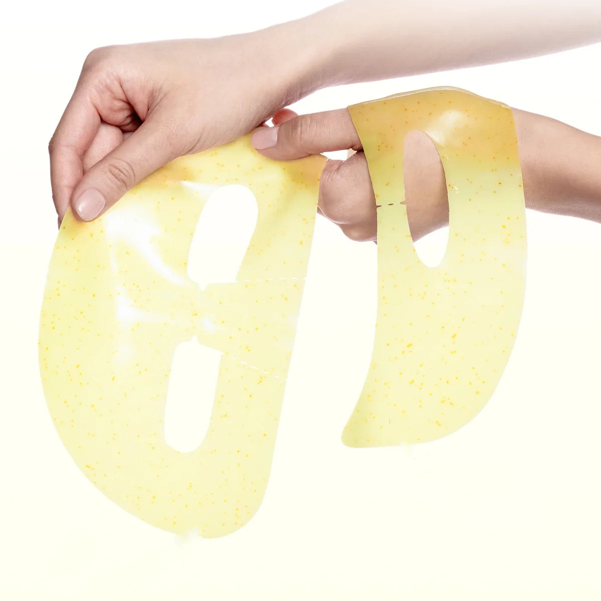 A person's hands holding a Celimax The Vita-A Retinol Shot Tightening 2-Step Gel Mask with small yellow speckles against a solid white background.