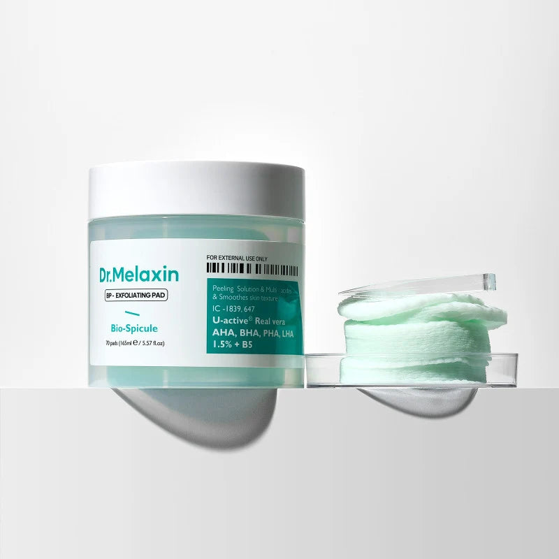 Dr. Melaxin Bio-Spincule exfoliating pad jar with its clear lid and a stack of mint-green cotton pads on a reflective white surface.