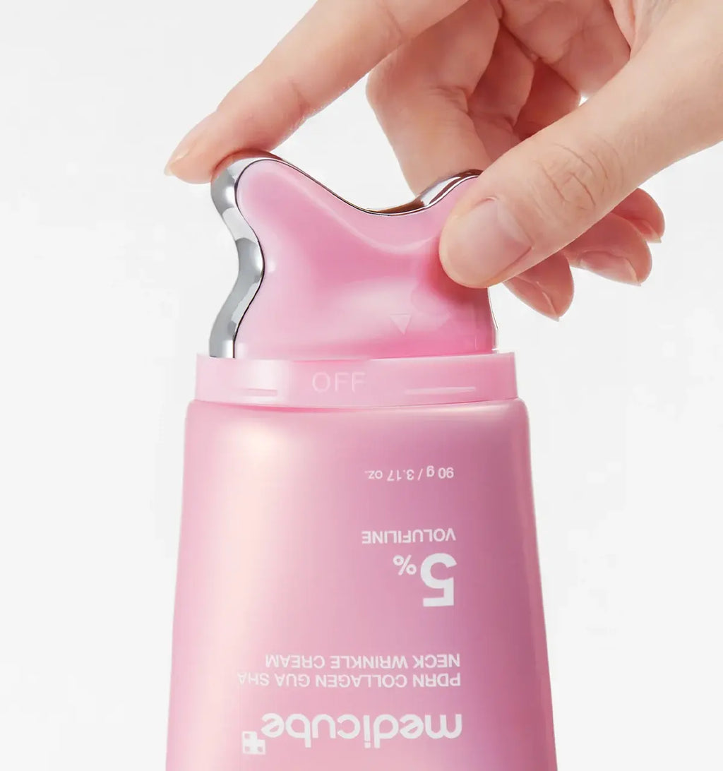 A close-up of a hand pressing the top button of a pink Medicube skincare pump bottle, with the bottle labeled '5% VOLUFININE' and 'medicube' visible against a clean white background.