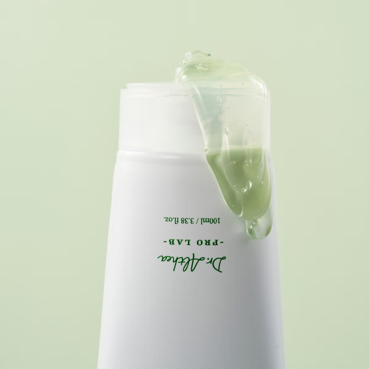 A Dr. Althea Green Relief Amino Gel Cleanser l dripping from the top, set against a solid pale green background. The bottle features green text reading 'Dr.