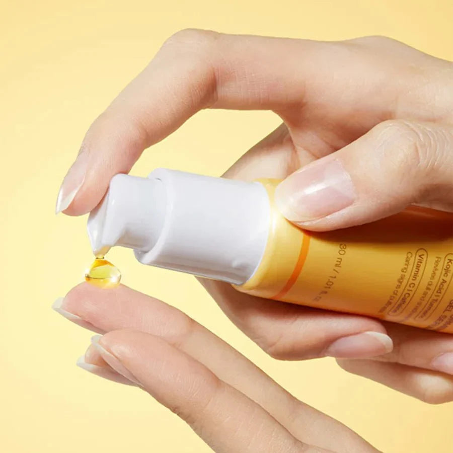 Hand applying medicube eye cream kojic acid against a yellow background