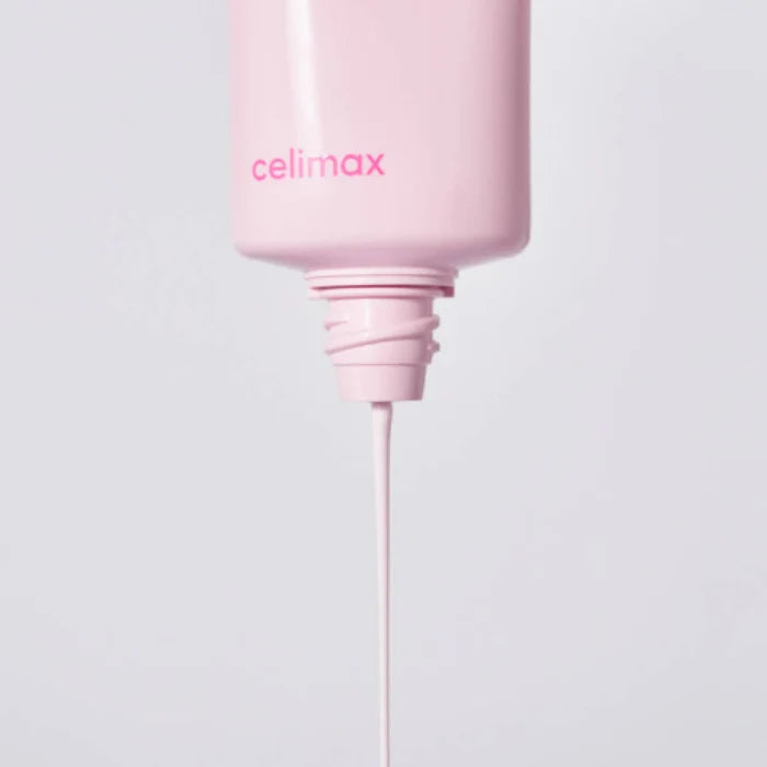 A close-up of a Celimax Heart Pink Tone Up Sun Cream with the brand name 'celimax' printed in pink on the front, with a thin white cream or liquid dripping from the nozzle against a light gray background.