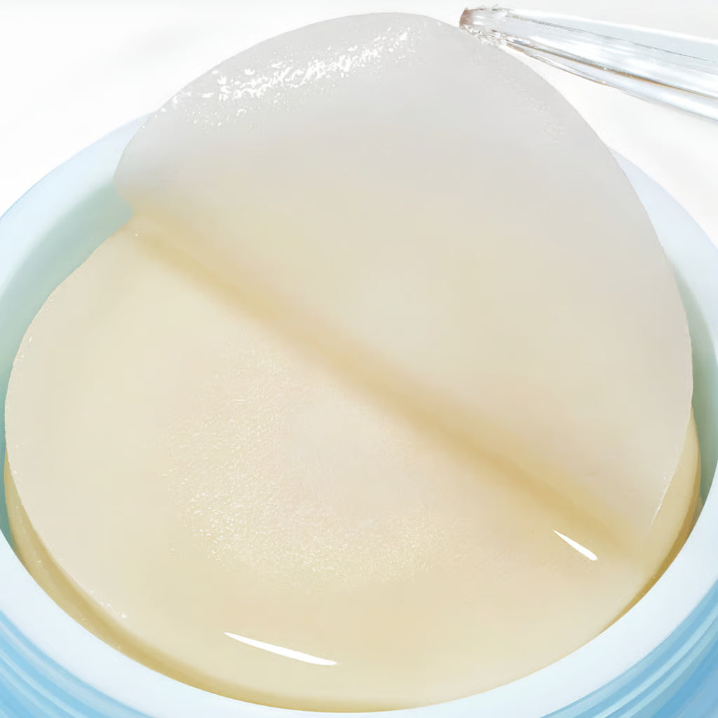 A close-up of a translucent, Anua Hyaluronic Acid 8 + Catechin Cool Calming Pad  or patch being lifted from a light blue container with a clear applicator.