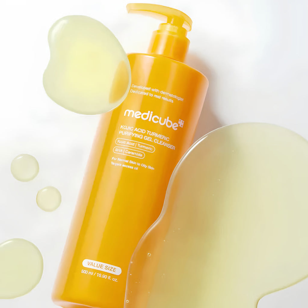 A bottle of Medicube Kojic Acid Turmeric Purifying Gel Cleanser  in a bright orange-yellow color, shown with decorative translucent droplets on a clean white background.